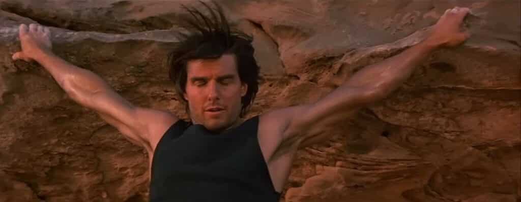 Tom Cruise hangs out on the side of a cliff with a “fingertip grip” as Ethan Hunt in Mission: Impossible 2.
